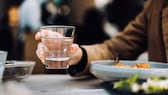 beim essen trinken: Frau hält beim Essen ein Glas Wasser in der Hand