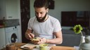 Mann schmiert sich Humus aufs Brot
