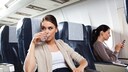 thrombose fliegen: Frau im Flugzeug trinkt Wasser