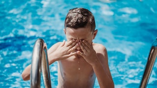 Junge reibt sich beim Verlassen eines Swimming Pools die Augen