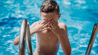 Junge reibt sich beim Verlassen eines Swimming Pools die Augen