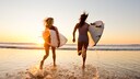 worauf surfer achten: Zwei Frauen mit Surfboards am Strand
