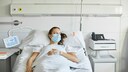 Frau liegt mit Maske im Krankenhaus