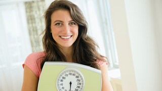 sich nicht wiegen: Junge Frau hält eine Waage
