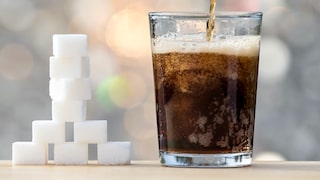 zuckerhaltige getränke leberkrebsrisiko: Zuckerstücke und ein Glas Cola