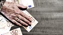 Die Hand eines &auml;lteren Menschen liegt auf Geldscheinen