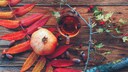 Weißdorntee auf einem Holztisch mit verschiedenen Herbstblättern drumherum