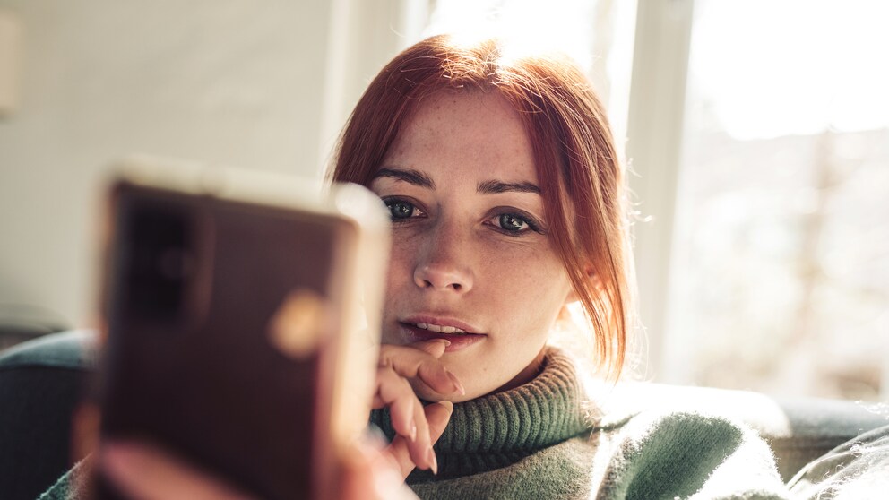nachrichtenkonsum ungesund: Frau guckt auf ihr Handy