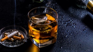 Perfektionismus Alkoholsucht: Ein Glas Whiskey neben Gläsern und einem Aschenbecher