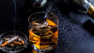 Perfektionismus Alkoholsucht: Ein Glas Whiskey neben Gläsern und einem Aschenbecher
