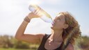 Frau trinkt bei Hitze aus Wasserflasche