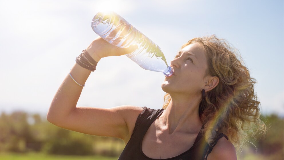 Frau trinkt bei Hitze aus Wasserflasche