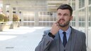 Mann mit Anzug popelt in der Nase