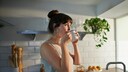 kaffee-abnehmen: Junge Frau steht in der Küche und trinkt Kaffee