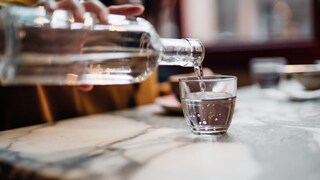 Frau schüttet Wasser in Glas