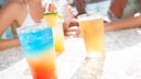 Junge Menschen mit Cocktails am Pool