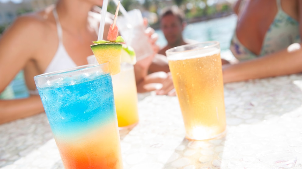 Junge Menschen mit Cocktails am Pool