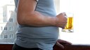 Bierbauch Alter vorbeugen: Mann mit Buachspeck und Bier in der Hand
