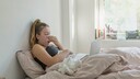 Junge Frau mit verschnupfter Nase im Bett