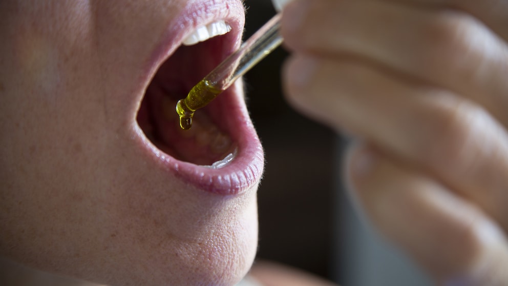 Frau träufelt sich CBD-Öl in den Mund