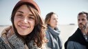 Drei junge, lächelnde Menschen am Nordseestrand