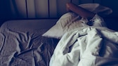 Frau liegt unter Kissen im Bett