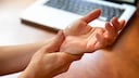 Mann greift sich ans Handgelenk