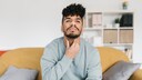 Junger Mann mit Halsschmerzen auf dem Sofa