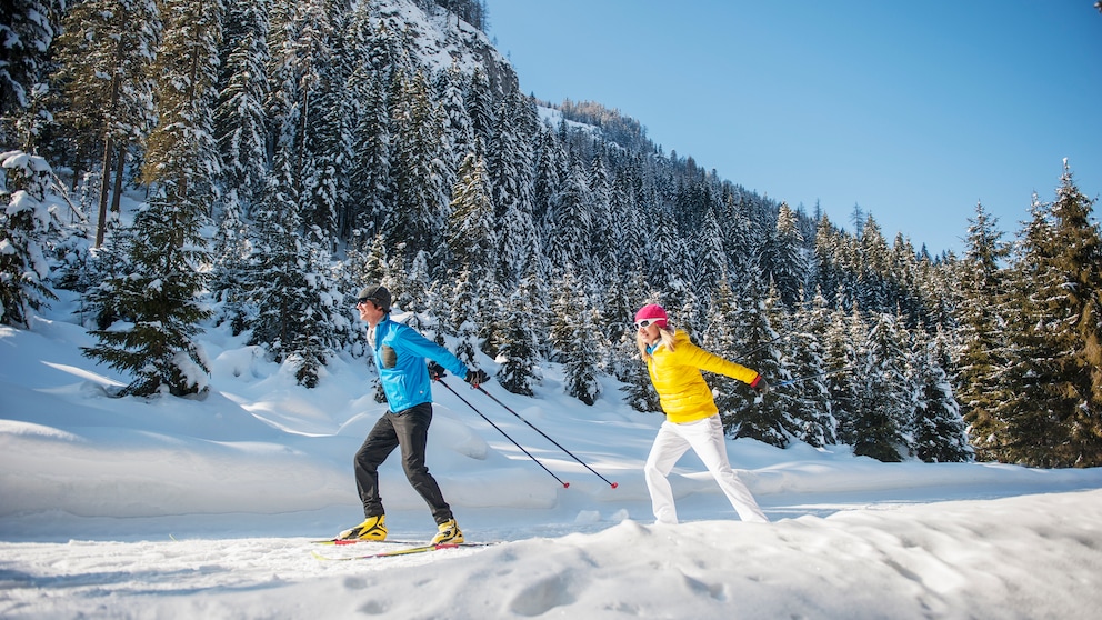 Mann und Frau beim Langlaufen in winterlicher Waldlandschaft