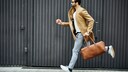 Mann in Jeans und Jacke sprintet mit Aktentasche in der Hand