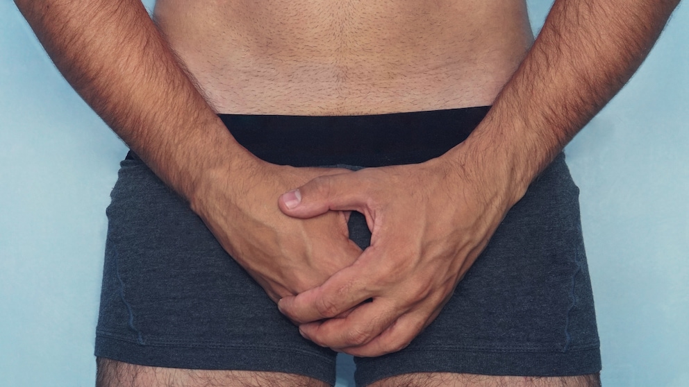 beschneidung mann gesund: Mann hält die Hände vor seinem Schoß