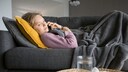 Frau liegt krank auf dem Sofa