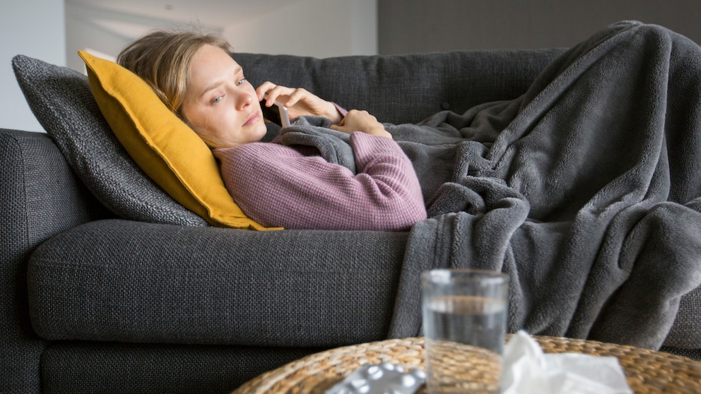 Frau liegt krank auf dem Sofa