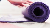 gymnastikmatten yogamatten test: Eine Frau rollt eine Matte zusammen