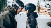 Vater und Sohn in Winterbekleidung und mit Skihelm und Brille