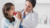 richtig inhalieren: Ärztin zeigt Mädchen den Umgang mit einem Inhalator