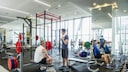 Menschen im Fitnessstudio beim Trainieren und Sprechen.