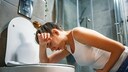 erbrechen gehirn: Frau beugt sich über die Toilette