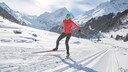 Die besten Skating-Langlaufski: Frau bei strahlendem Sonnenschein beim Langlaufen