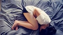 PMDS: Frau liegt eingerollt im Bett
