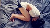 PMDS: Frau liegt eingerollt im Bett
