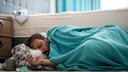 Verschnupfter Mann schl&auml;ft auf dem Boden vor dem Bett