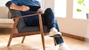 Mann sitzt mit &uuml;berschlagenen Beinen