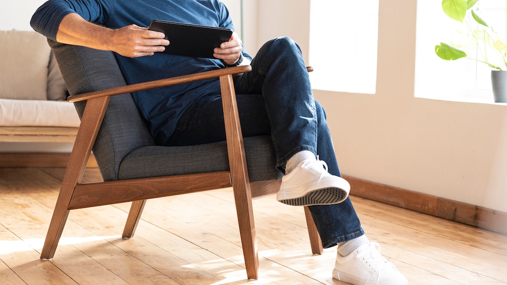 Mann sitzt mit überschlagenen Beinen