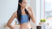 Fasten und Training: Junge Frau im Sport-Outfit trinkt ein Glas Wasser