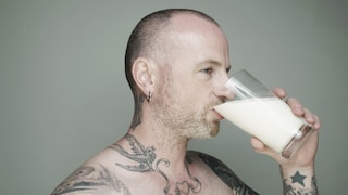 Tätowierter Mann trinkt Milch