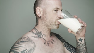 Tätowierter Mann trinkt Milch