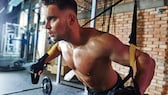 TRX- Schlingentraining: Mann absolviert Übung im Gym