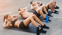 Was ist ein Ab Workout? Sportliche Frauen und Männer machen Sit-ups