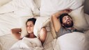 Frau h&auml;lt sich im Bett Ohren zu, weil Partner laut schnarcht